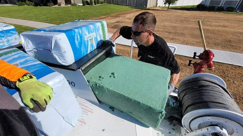Loading wood fiber mulch into a hydroseeder tank, the dyed green tracer color visible